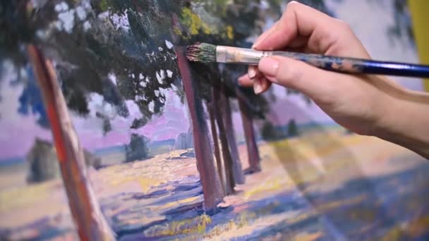 De hand van de kunstenaar met een borstel glijdt over het doek van het schilderij — Stockvideo