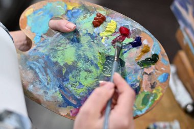 Renkli palet ve yağlı boya. Yakın plan, yüzü yok.