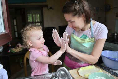 Anne ve küçük kızı mutfakta yemek hazırlarken iyi eğlenceler. Pencereden görüntüle