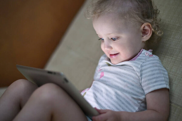 Ребенок с энтузиазмом смотрит мультфильмы на планшете, вид сбоку