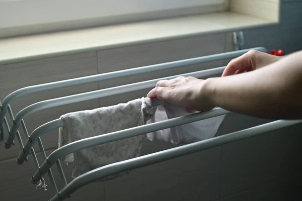 一个女人把洗好的婴儿衣服挂在烘干机上 妈妈的日常事务 靠近点 — 图库照片