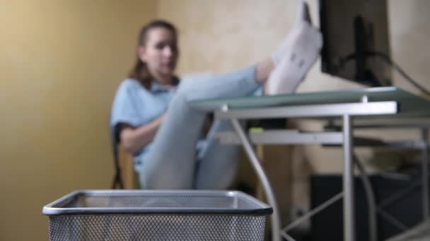 Fille s'assoit imposamment à une table et jette des morceaux de papier froissés dans la poubelle — Video