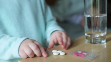 Yatağın başucundaki masadan hap alan çocukların yakın plan fotoğrafları.