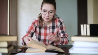 Kız sınavlara hazırlanıyor, bir kitapta malzeme arıyor, sayfaları karıştırıyor.