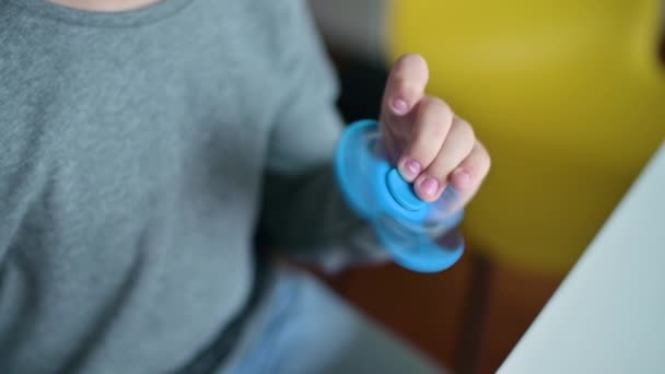 Een speelgoedspinner draait in de handen van een jongen. Hij is aan het rotzooien. — Stockvideo