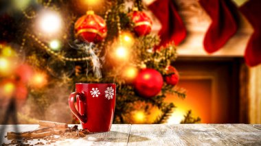 Reklam ürünleriniz için yeri olan ahşap bir masa. Bulanık yeşil Noel ağacı, şömine alevler ve Noel Baba arka planında kırmızı çoraplar..
