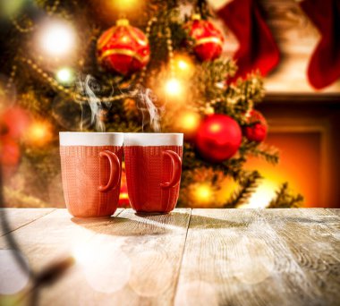 Reklam ürünleriniz için yeri olan ahşap bir masa. Bulanık yeşil Noel ağacı, şömine alevler ve Noel Baba arka planında kırmızı çoraplar..