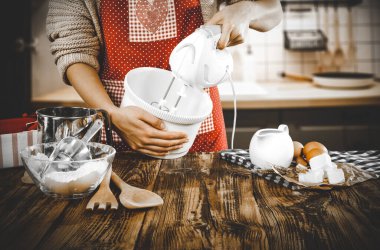 Şefin kadın elleri mutfaktaki ahşap masada yemek hazırlıyor. Pasta ve ekmek pişiriyorum. Mutfak geçmişi olan kırmızı önlüklü bir kadın..