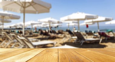 Masa arkası, güzel mavi okyanus ve kumlu sahil manzaralı. Sandalyeli bir masa ve deniz mesafesi. Yaz güneşli bir gün.