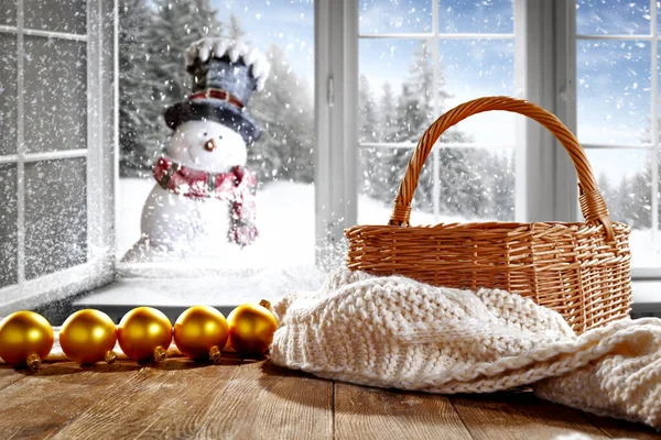 White snowy winter window background with space for your products and decoration. Blurred landscape of mountains and snowman. Happy Christmas time.