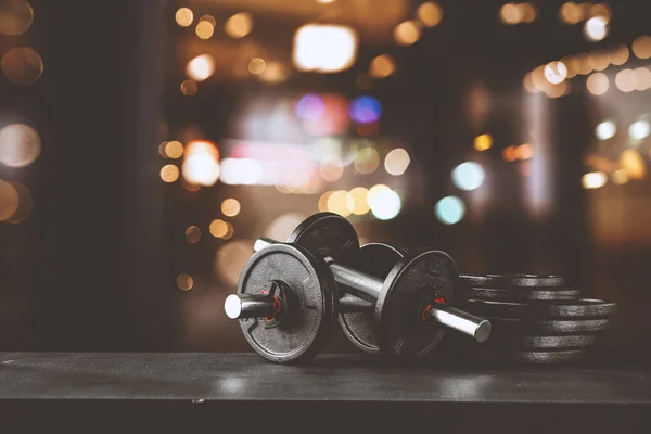 Dumbbell, barbell and workout in the gym. Space for products and decorations or text with blurred gym background.