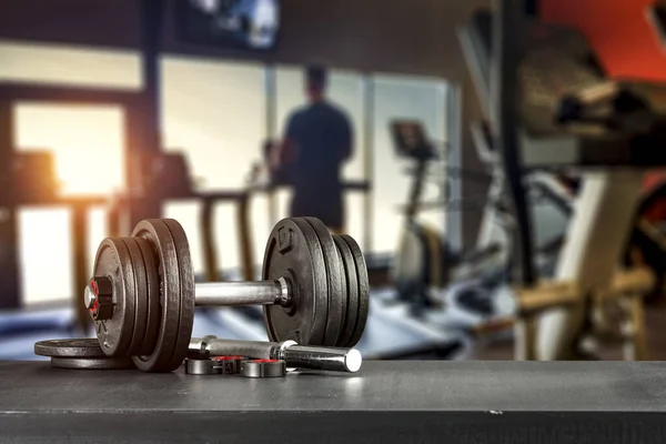 Dumbbell, barbell and workout in the gym. Space for products and decorations or text with blurred gym background.