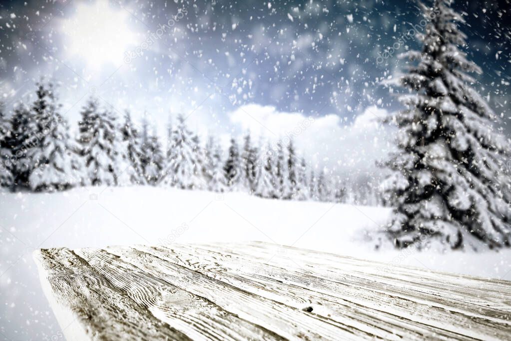 Snowy winter glimmering and shiny landscape with wooden board top and space  for products and decorations.