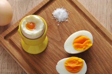 Tahta tepside, haşlanmış yumurta, tuz ve haşlanmış yumurtanın iki yarısı. Ahşap ışık arka plan. Yukarıdan görüntüleyin. Close. 