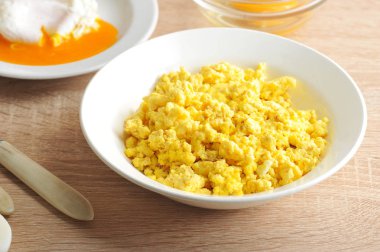 Beyaz derin bir tabakta tavuk yumurtalarından çırpılmış yumurta. Close. Açık ahşap arka plan.