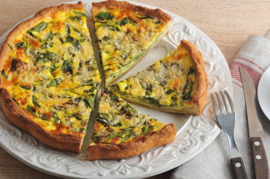 Beyaz bir tabak üzerinde ıspanak ile quiche açık pasta. Pasta porsiyonlar halinde kesilir. Çatal çatal ve bıçak.