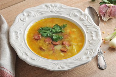 Füme etli kokulu bezelye çorbası. Tabağın yanında bez ve kaşıktan yapılmış bir peçete var. Close. Makro fotoğrafçılık.