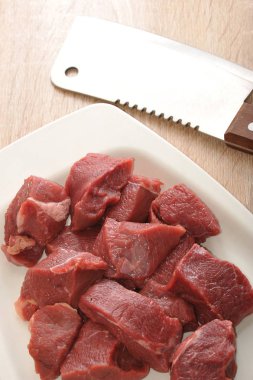 Beyaz bir tabak ta çiğ sığır eti dilimleri. Kıyma veya gulaş yapmak için et. Et kesmek için bir bıçak var. Yukarıdan görüntüleyin. Close. Makro fotoğrafçılık.