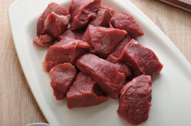 Beyaz bir tabak ta çiğ sığır eti dilimleri. Kıyma veya gulaş yapmak için et. Et kesmek için bir bıçak var. Yukarıdan görüntüleyin. Close. Makro fotoğrafçılık.