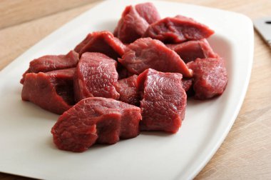 Beyaz bir tabak ta çiğ sığır eti dilimleri. Kıyma veya gulaş yapmak için et. Et kesmek için bir bıçak var. Yukarıdan görüntüleyin. Close. Makro fotoğrafçılık.