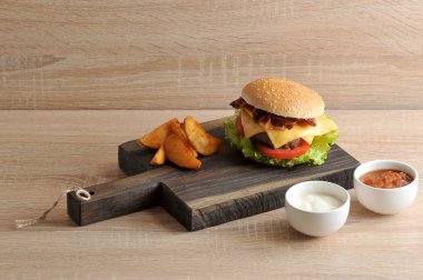 Hamburger ve patates ahşap bir tahta üzerinde rustik vardır. Mayonez ve ketçap ile sonraki bardaklar. Hamburger dolması doğranmış et pirzama, kızarmış pastırma, marul yaprakları, peynir, domates, sos içerir.