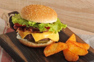 Hamburger ve patates ahşap bir tahta üzerinde rustik vardır. Hamburger dolması doğranmış et pirzama, kızarmış pastırma, marul yaprakları, peynir, domates, sos içerir. 
