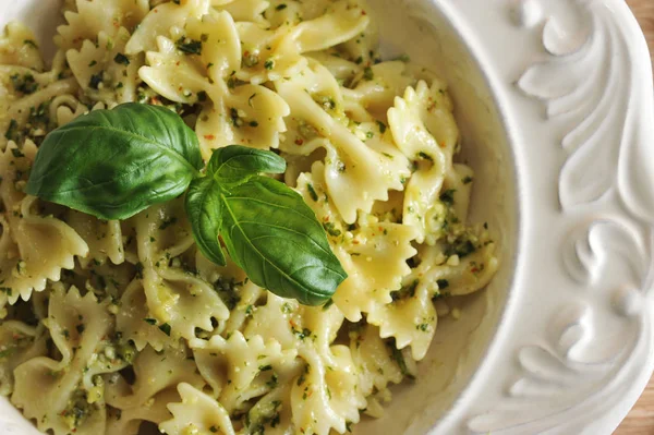 Beyaz bir tabakta pesto soslu makarna farfalle. Yemek taze fesleğen yaprağı ile dekore edilmiştir. Yukarıdan görüntüleyin. Close. Makro fotoğrafçılık.