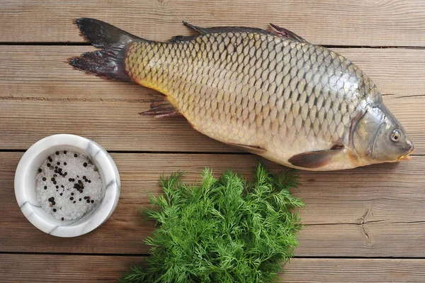 Ahşap bir yüzeyde sazan. Tuz ve biber ile dereotu ve harç yeşillik yanında. Sazan mükemmel bir Noel yemeğidir. Yukarıdan görüntüleyin. Close.