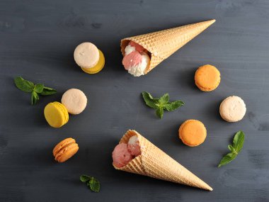  Çilekli dondurma ile çok renkli makarna ve gofret bardak. Nane yapraklarının yanında. Koyu ahşap arka plan. Yukarıdan görüntüleyin. Close.