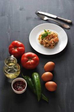 Domates ile geleneksel Türk kızartılmış yumurta pişirme için malzemeler. Çerçevede, tavuk yumurta, domates, acı yeşil biber, zeytinyağı, baharat ve pişmiş çırpılmış yumurta bir tabak. Yukarıdan görüntüle.