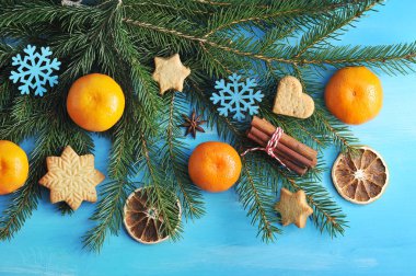Ladin dalları, mandalina, kurabiye, tarçın çubukları, kurutulmuş portakal dilimleri ve kar taneleri şeklinde bir Noel ağacı oyuncak Noel kompozisyonu. Mavi ahşap arka plan. Close. Makro fotoğrafçılık.