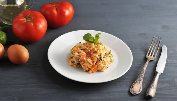 Domatesli geleneksel Türk yumurtası (menemen). Domates, yumurta, yeşil biber: pişirme için yakındaki malzemeler omlet. Çatal bıçak takımı nın çerçevesinde. Close.