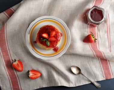 Çilek reçeli ile doldurulmuş ve taze çilek ile dekore krep tabaklarında. Bankanın yanında çilek reçeli, bir çay kaşığı, çilekli çilek. Close. Yukarıdan görüntüle.