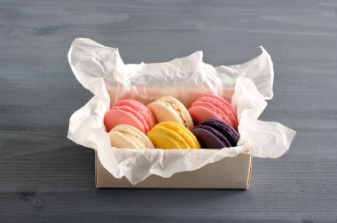 Dikdörtgen bir kutuda hamur işi makarnalar. Ahududu, vanilya, limon ve yaban mersini makarna bir dizi. Koyu ahşap arka plan. Close. Makro fotoğrafçılık.