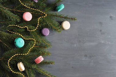 Çok renkli macaroons ve altın boncukile süslenmiş bir ladin dalından Noel kompozisyonu. Koyu ahşap arka plan. Yukarıdan görüntüleyin. Close. Metnin altına yerleştirin.