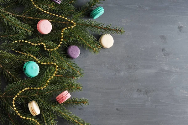 Çok renkli macaroons ve altın boncukile süslenmiş bir ladin dalından Noel kompozisyonu. Koyu ahşap arka plan. Yukarıdan görüntüleyin. Close. Metnin altına yerleştirin.