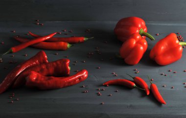 Tatlı biber, Ramiro, koyu bir yüzeyde acı biber. Bütün biberler kırmızı. Etrafında pembe biber dağınık bezelye vardır. Close.