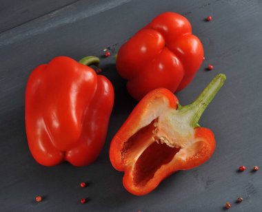 Kırmızı tatlı biber. İki buçuk. Yüzeyde pembe biber bezelye dağınık. Karanlık arka plan. Close.