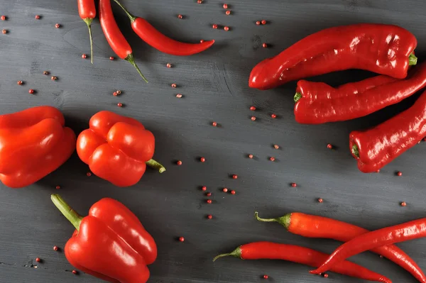 Tatlı biber, Ramiro, koyu bir yüzeyde acı biber. Biberin tamamı kırmızı. Etrafında pembe biber dağınık bezelye vardır. Close. Yukarıdan görüntüle.