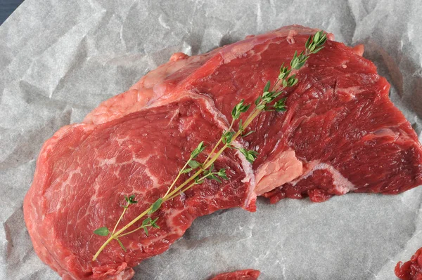 Parşömen kağıdında çiğ biftek. Biftek te kekik bir dal. Yukarıdan görüntüleyin. Close. Makro fotoğrafçılık.