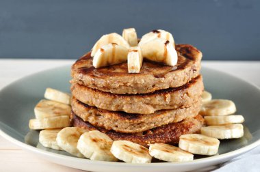 Muz ve çikolata şurubu ile karabuğday krep. Krepli bir tabak muz dilimleri ile dekore edilmiştir. Ahşap arka plan. Close. Makro fotoğrafçılık.