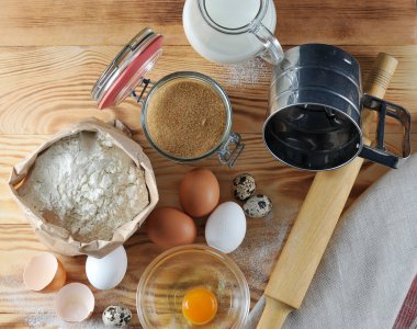 Pişirme için ayarlayın. Resimde, süt, un, bıldırcın yumurtası ve yumurta, bir oklava, bir un elemek, bir kase protein ile bir sarısı ve bir yumurta kabuğu bir sürahi. Ahşap arka plan. Close. Yukarıdan görüntüle.