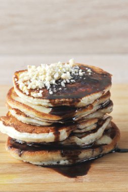 Krepler tahta bir tahtaüzerine serilir. Krep çikolata şurubu ile dökülür ve fındık kırıntıları ile dekore edilmiştir. Açık ahşap arka plan. Çerçevenin dikey yönü. Close.