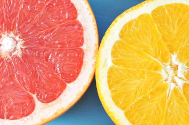 Bir dilim olgun portakal ve bir dilim sulu pembe greyfurt. Mavi ahşap arka plan. Yukarıdan görüntüleyin. Close. Makro fotoğrafçılık.