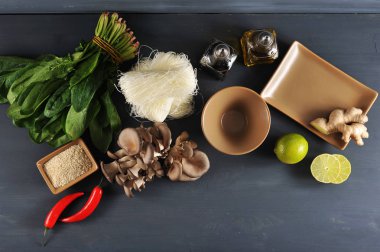 Bir wok erişte pişirmek için bir set. Çerçevede, pirinç eriştesi, taze ıspanak, istiridye mantarı. Limon, susam, zencefil kökü, biber. Boş tabak ve kase. Close. Yukarıdan görüntüle.