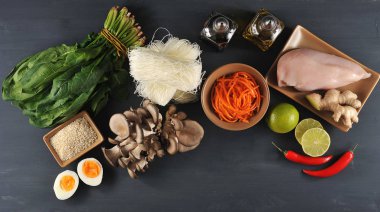 Bir wok erişte pişirmek için bir set. Çerçevede, pirinç erişte, taze ıspanak, tavuk eti, istiridye mantar, baharatlı salata havuç. Limon, susam, zencefil kökü, biber. Close. Yukarıdan görüntüle.