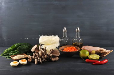 Bir wok erişte pişirmek için bir set. Çerçevede, pirinç erişte, taze ıspanak, tavuk eti, istiridye mantar, baharatlı salata havuç. Kireç, susam, zencefil kökü, biber, soya sosu ve susam yağı. Closeup