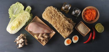 Bir wok erişte pişirmek için bir set. Çerçevede, buğday erişte, tavuk, Çin lahanası, istiridye mantarı, baharatlı havuç, kireç, susam, zencefil kökü, biber. Close. Yukarıdan görüntüle.