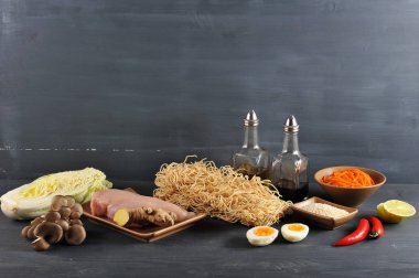 Bir wok erişte pişirmek için bir set. Çerçevede, buğday erişte, tavuk, Çin lahanası, istiridye mantarı, baharatlı havuç, kireç, susam, zencefil kökü, biber. Karanlık arka plan. Close. 