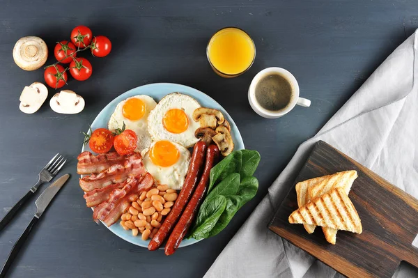 Yedi malzemeden oluşan geleneksel İngiliz kahvaltısı. Kızarmış pastırma, sosis, kızarmış taze domates ve champignons, domates soslu beyaz fasulye, tost, kızarmış yumurta. Karanlık arka plan. Yukarıdan görüntüle.